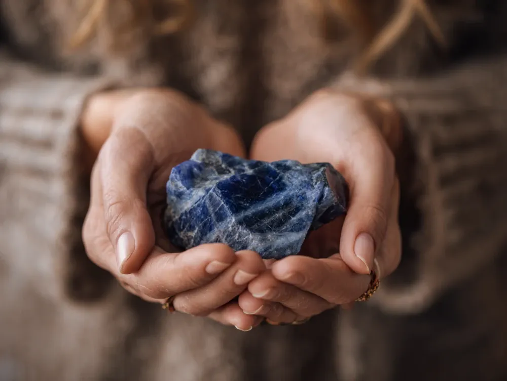 Women holding raw sodalite mineral meditating